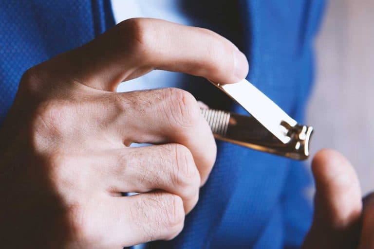 Man cutting fingernails using nail clipper, How Long Should Men's Nails Be?