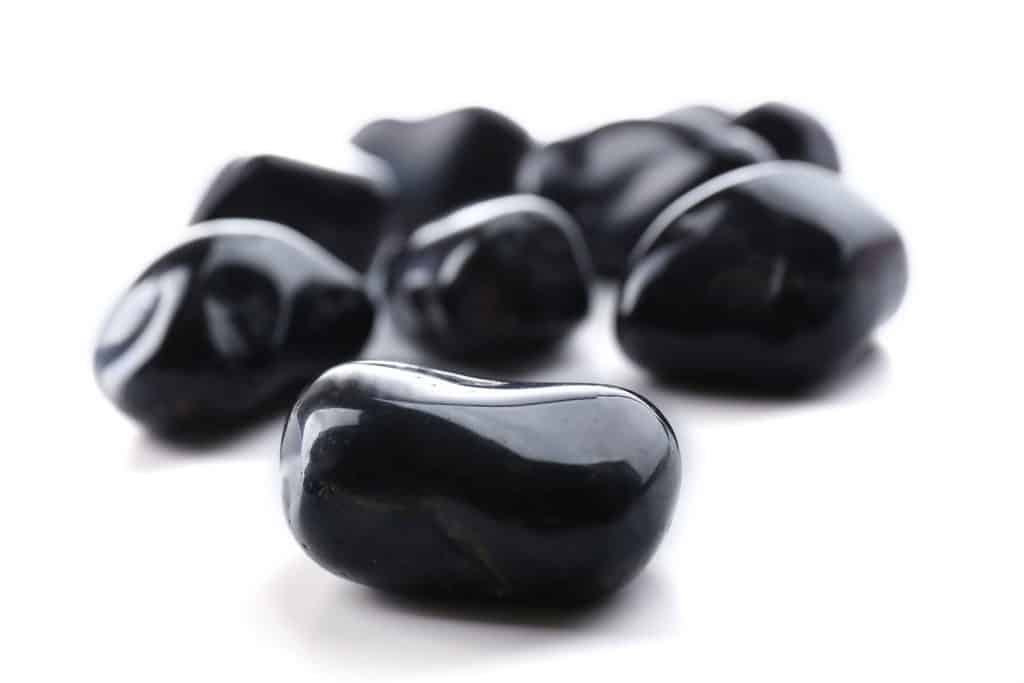 A pile of black onyx gemstones on a white background