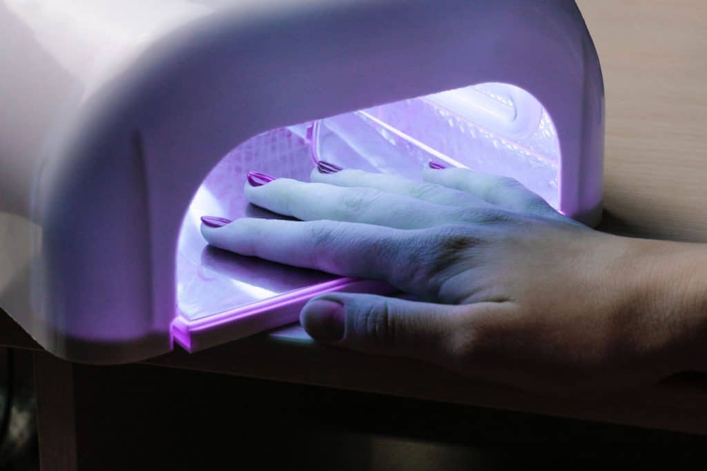 A woman drying her gel nail polish under an ultra violet light