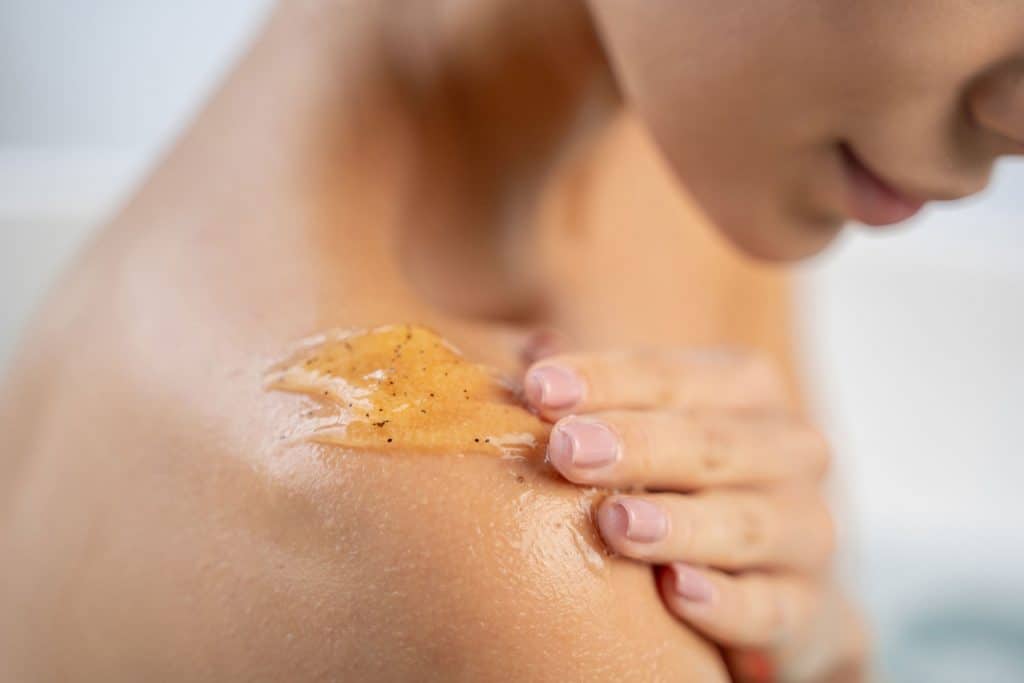 A woman putting body cleanser on her shoulder