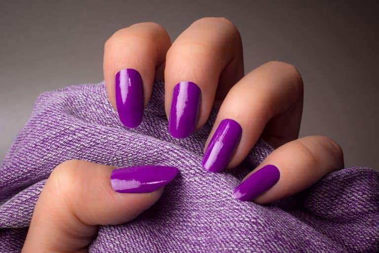 A woman showing her violet colored vinyl nail polish, How To Change Acrylic Nail Color [5 Steps]