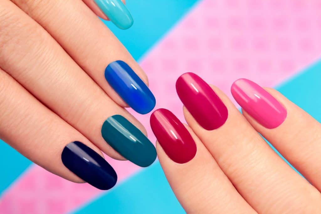 Blue pink nail Polish on long nails on a colored background.