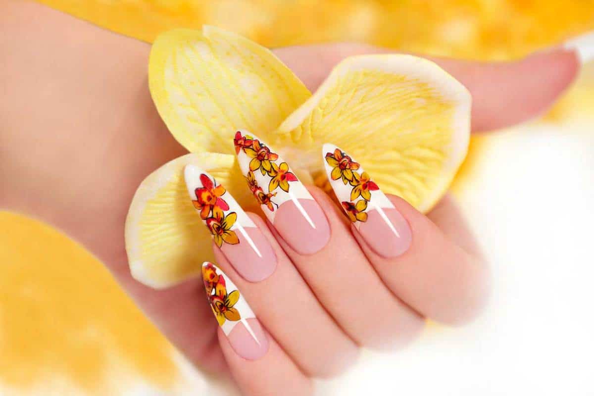 Hand with manicured nail holding yellow orchids