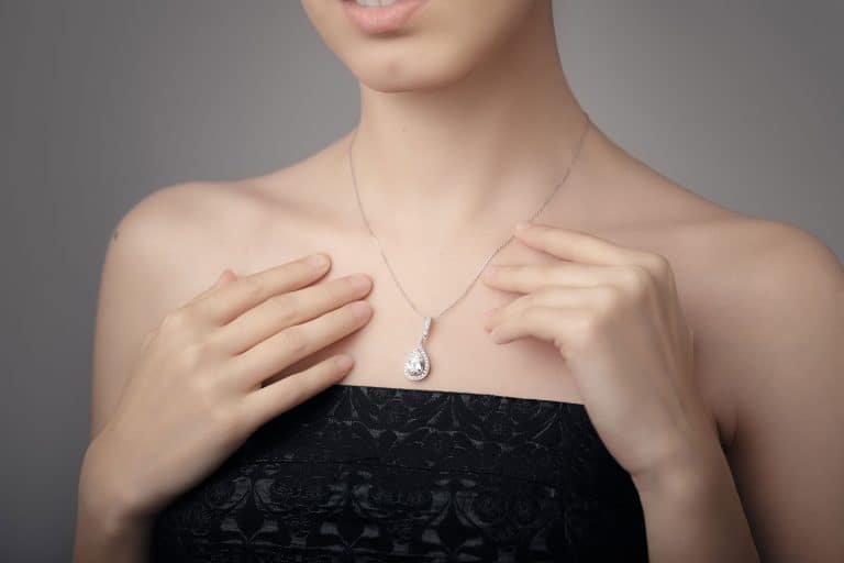 A beautiful woman wearing a silver necklace with a diamond pendant, How To Wear A Necklace: 5 Must-Know Tips