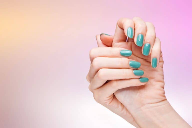 A woman showing her sky blue colored acrylic nail designs on a gradient background, How Long Do Acrylic Nails Last?