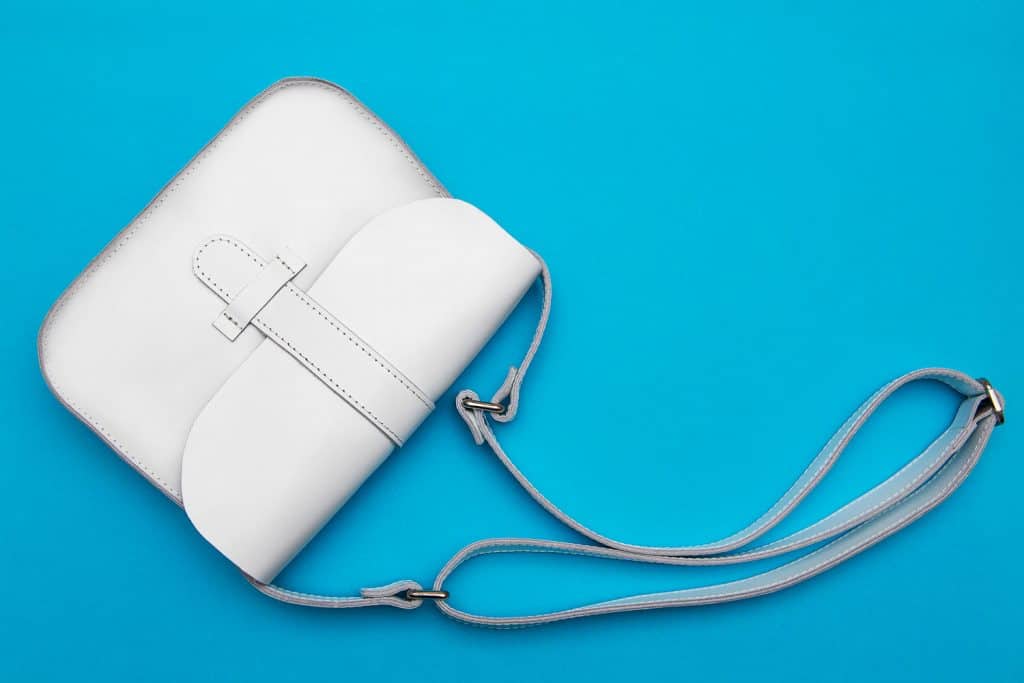 White woman leather purse with long handle on blue background