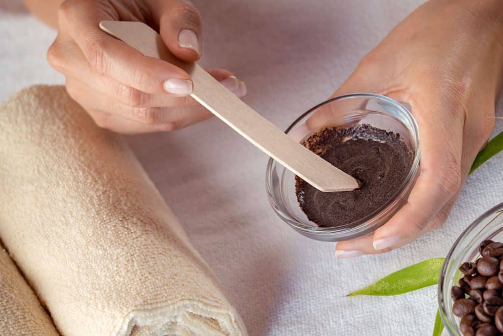 Young woman mixing ingredients for coffee body scrub treatment, 10 Best Body Scrubs For Aging Skin