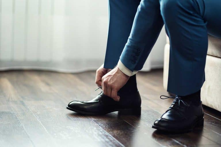 A businessman in suit tying his black leather shoes, What Color Of Shoes Should You Wear With A Blue Suit?