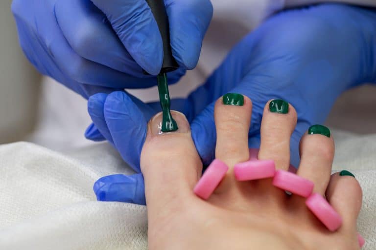 A pedicure expert putting green gel pedicure on her clients nails, How Much Does A Gel Pedicure Cost?