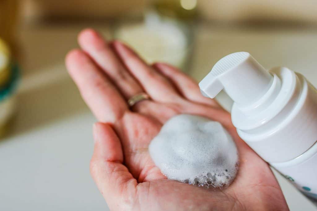 A woman pouring cleanser on her hand