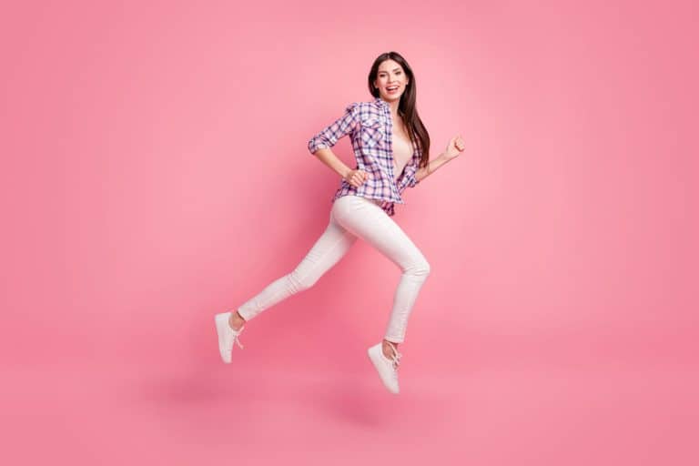 A woman wearing a checkered shirt pink shirt and white jeans with matching white shoes, What Color Shoes Can You Wear With White Jeans?