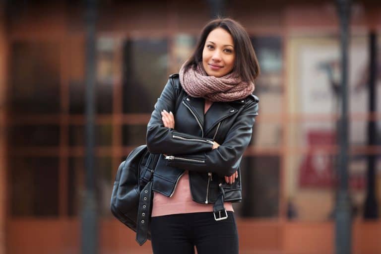 A woman wearing a leather jacket and scarf in the cold New York weather, Should A Leather Jacket Be Tight Or Loose?