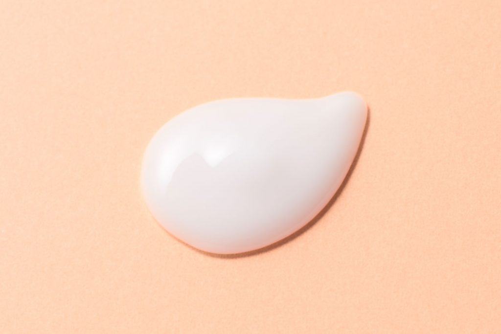 An up close photo of a milky lotion on a beige background