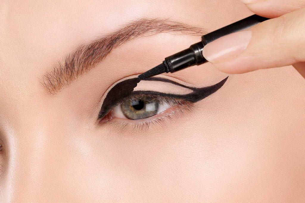 Beautiful model applying eyeliner closeup on eye