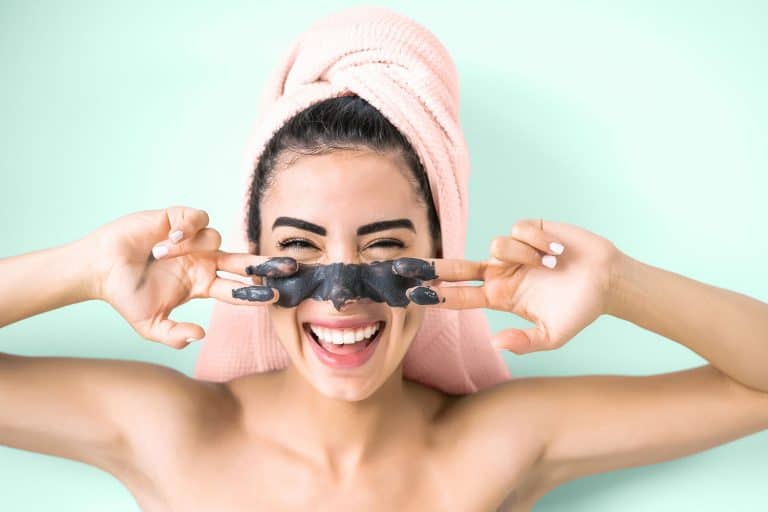 Happy smiling girl applying facial charcoal mask portrait - Young woman having skin care cleanser spa day, Do Clay Masks Absorb Oil And Do They Clean Pores?