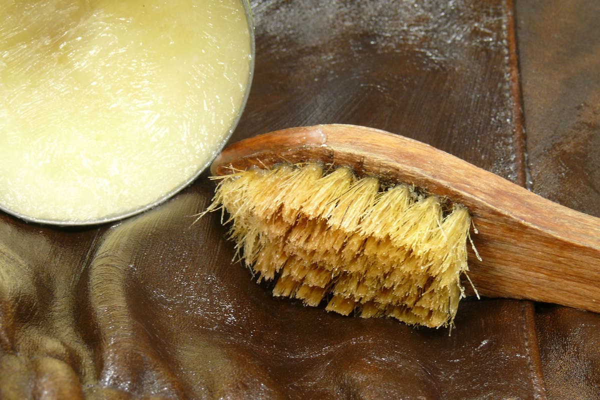 Leather cream and a wooden brush on leather