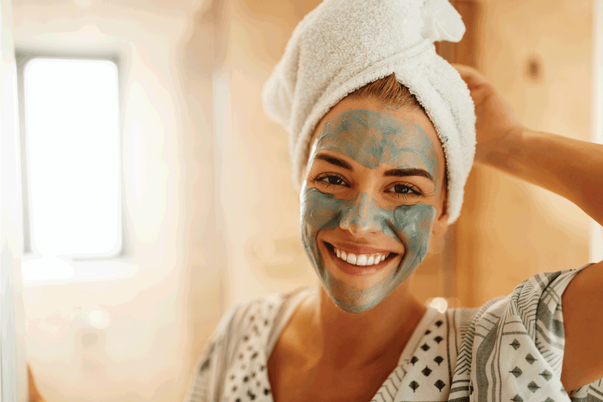 Portrait of an attractive young woman standing in the bathroom with a facial mask