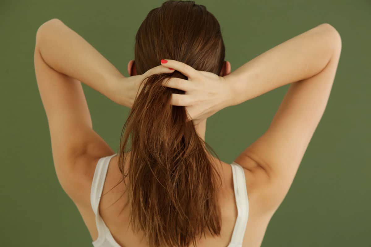 Студийный снимок женщины, наносящей масло для волос пальцами