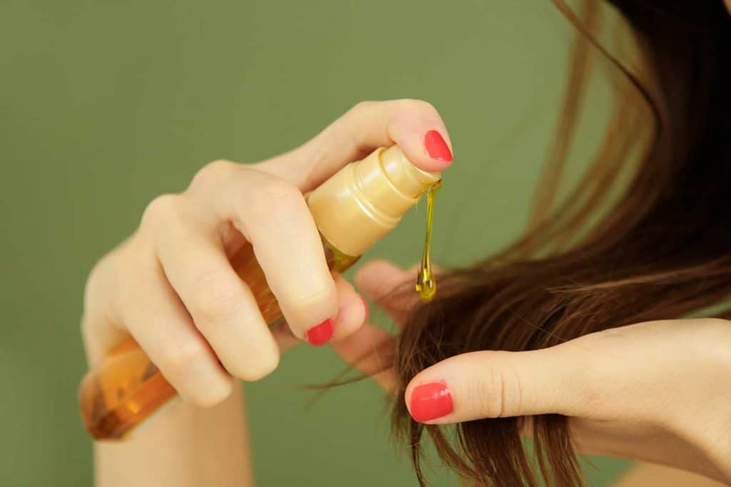 Женщина, наносящая масло на кончики волос
