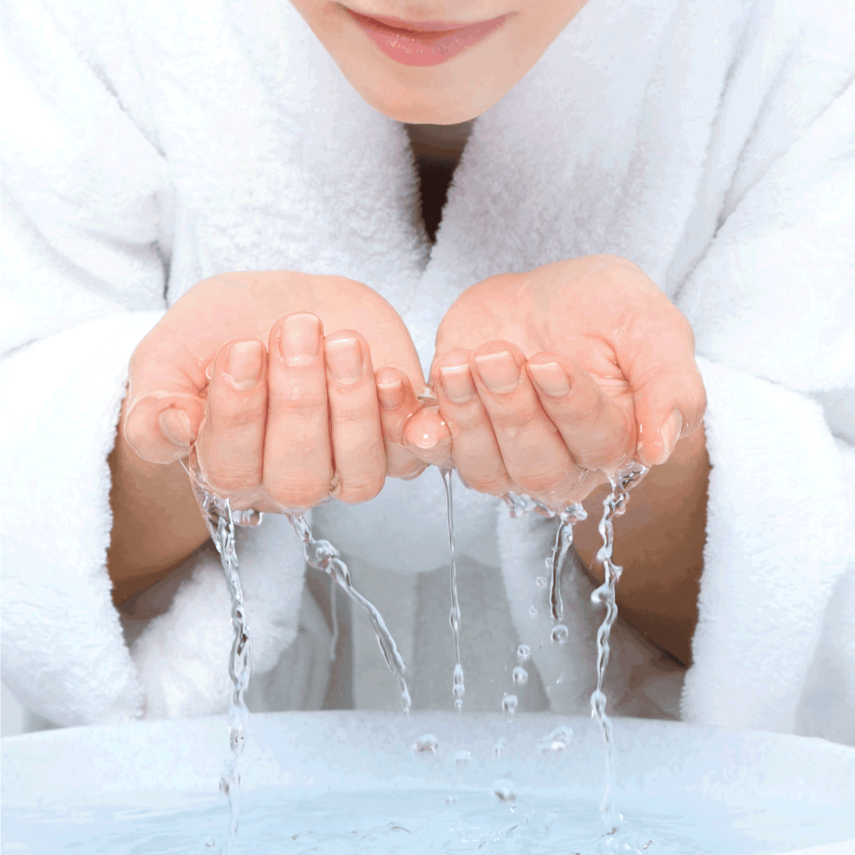 Young woman in white bath robe washing face