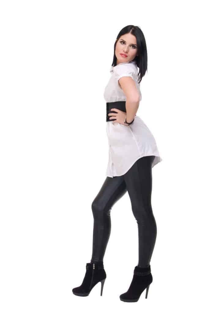 A beautiful woman wearing a faux leather pants and a white dress on a white background