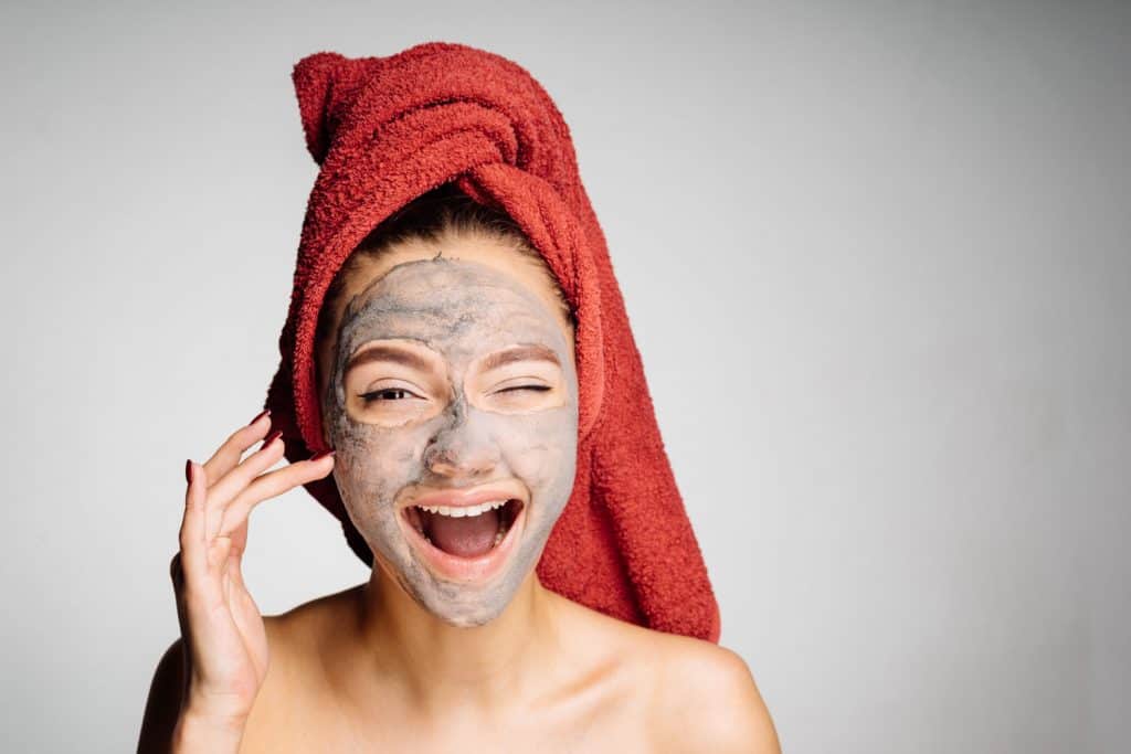 A happy woman getting her clay mask treatment on spa day