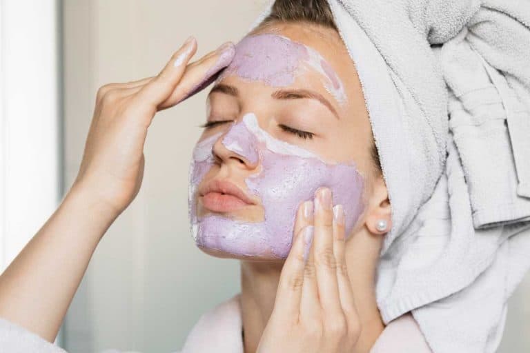 Attractive young woman putting on a beauty mask, applying it on her face, What Are The Typical Clay Mask Ingredients?
