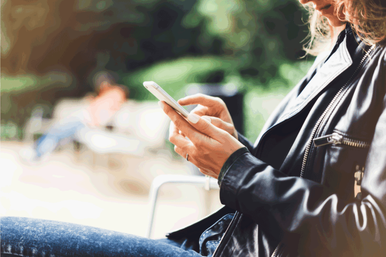 Girl-in-leather-jacket-holding-smart-phone-on-bench.-How-To-Dye-A-Leather-Jacket-And-Change-Its-Color