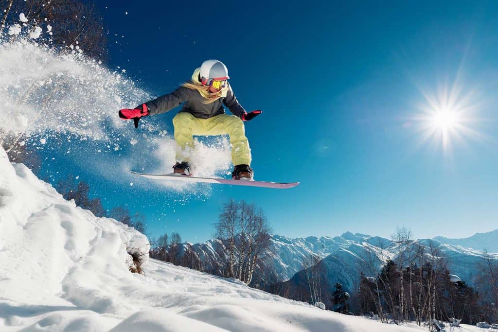 Girl jumping with snowboard from the hill