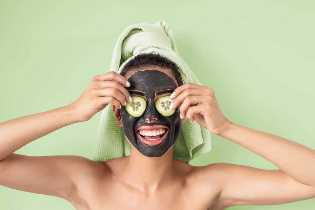 Happy smiling girl applying facial carbon mask portrait