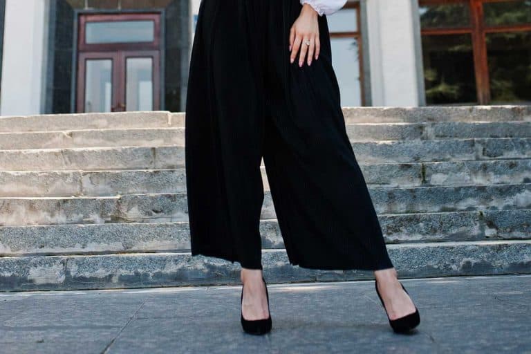 Fabulous woman in white blouse and broad black pants posing on the stairs, What Shoes To Wear With Palazzo Pants? [5 Great Options]