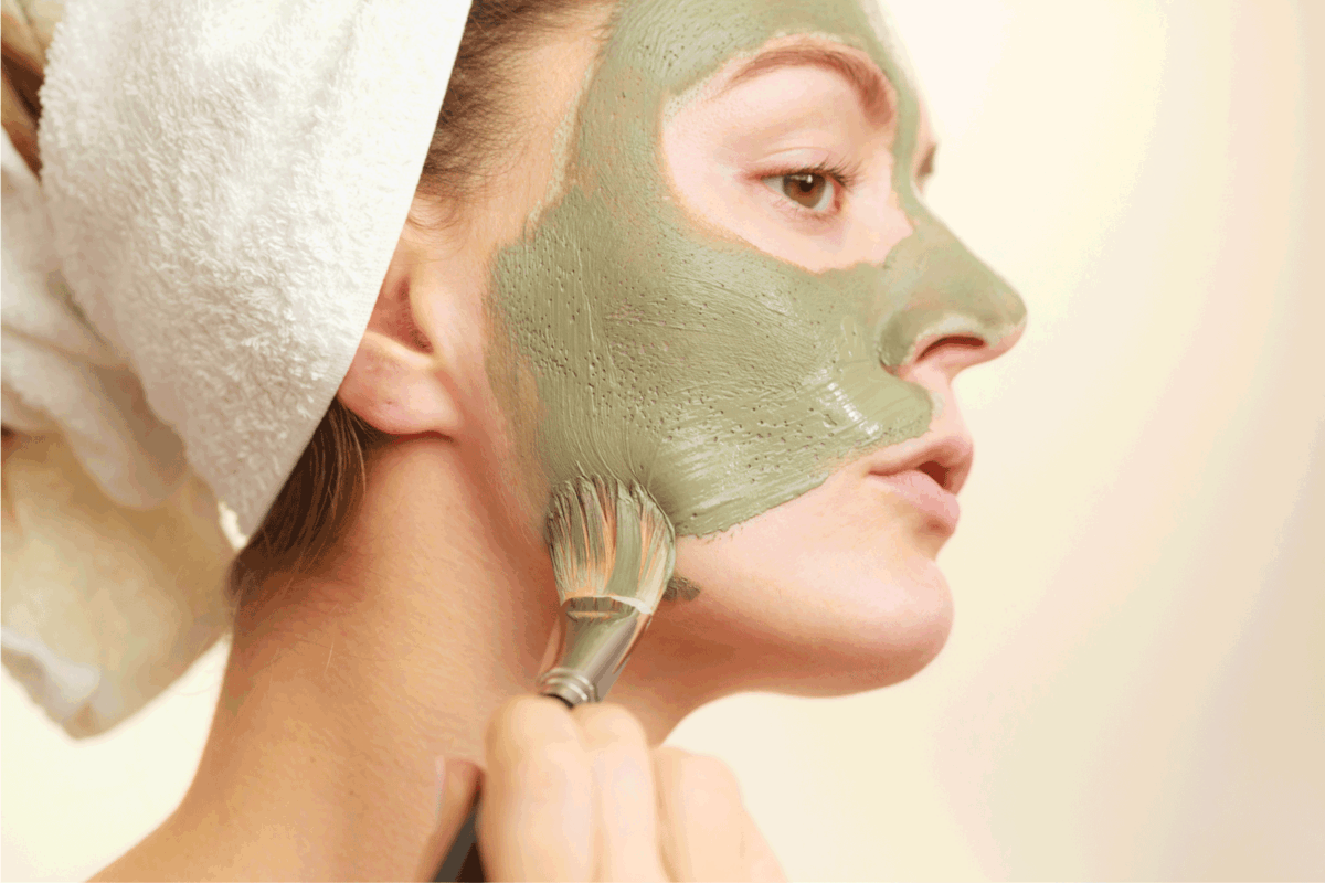 Skin care. Woman applying with brush clay mud mask to her face. Girl taking care of oily complexion. Beauty treatment.