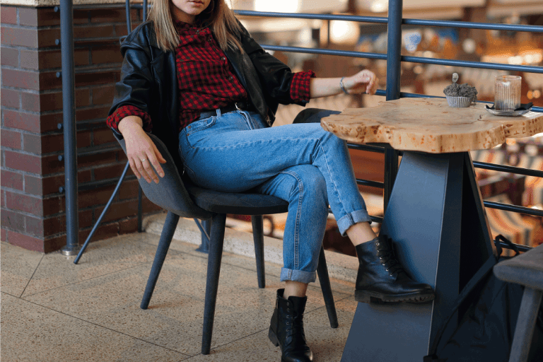 young beautiful stylish modern girl sitting at a table in a cafe waiting for friends after shopping. What Shoes Do You Wear With A Leather Jacket