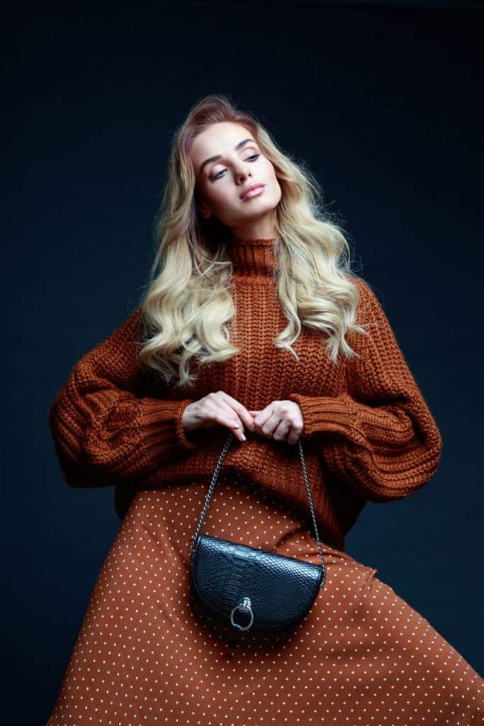 A blonde woman wearing a brown sweater and a polka dot skirt