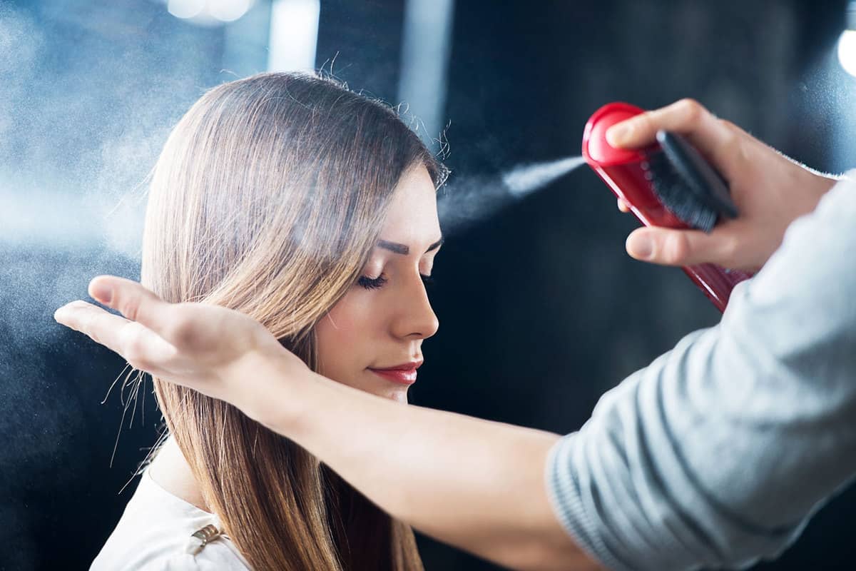 Hairdresser spraying his customer's hair