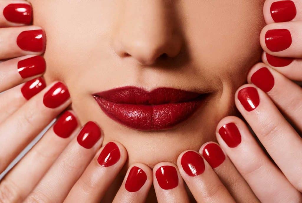 Hands touching the face of a woman wearing red lipstick