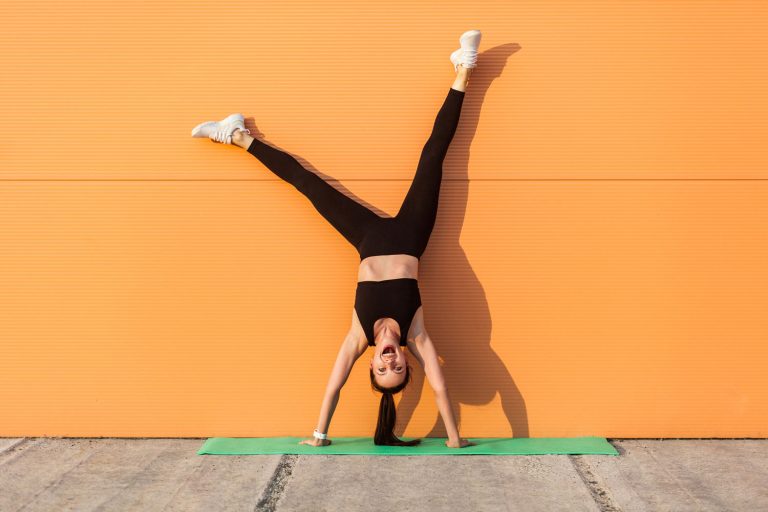 Overjoyed excited girl with perfect athletic body in tight sportswear doing yoga handstand pose against wall and laughing, shouting from happiness, Do Yoga Pants Have Built In Underwear?