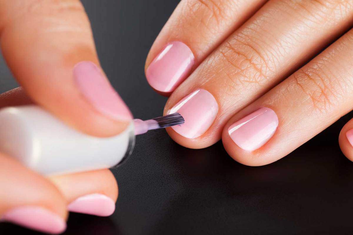 Woman painting nails with pink manicure