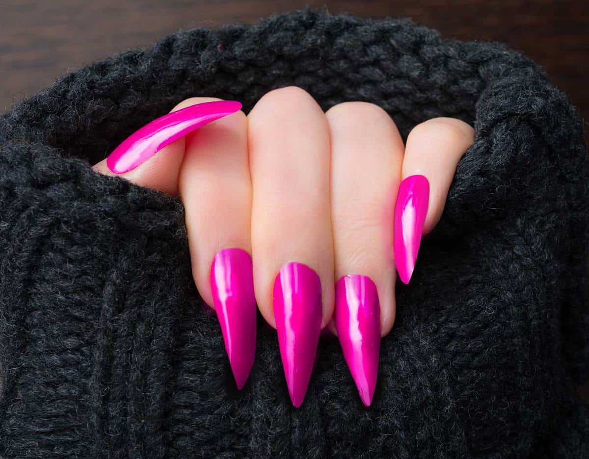 Woman showing her pink stiletto shaped nails in warm cardigan
