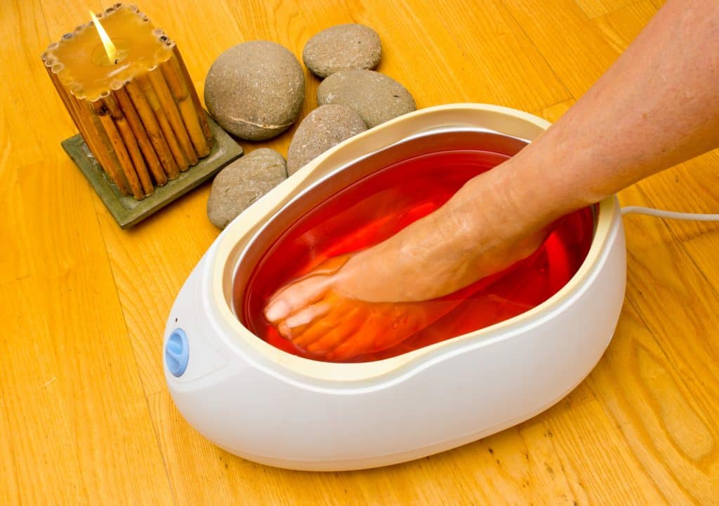 woman foot treatment in paraffin bath at the spa