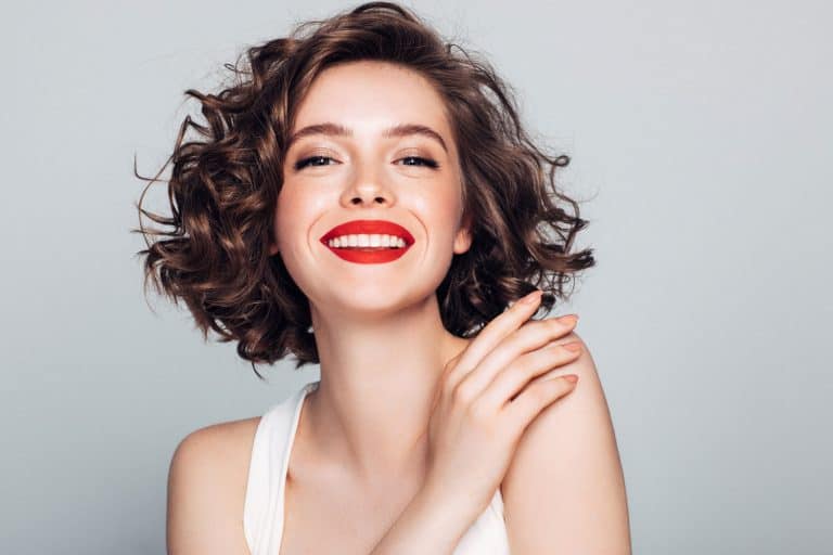 A beautiful curly haired woman wearing a white top and red lipstick, Does Red Lipstick Go With Everything?