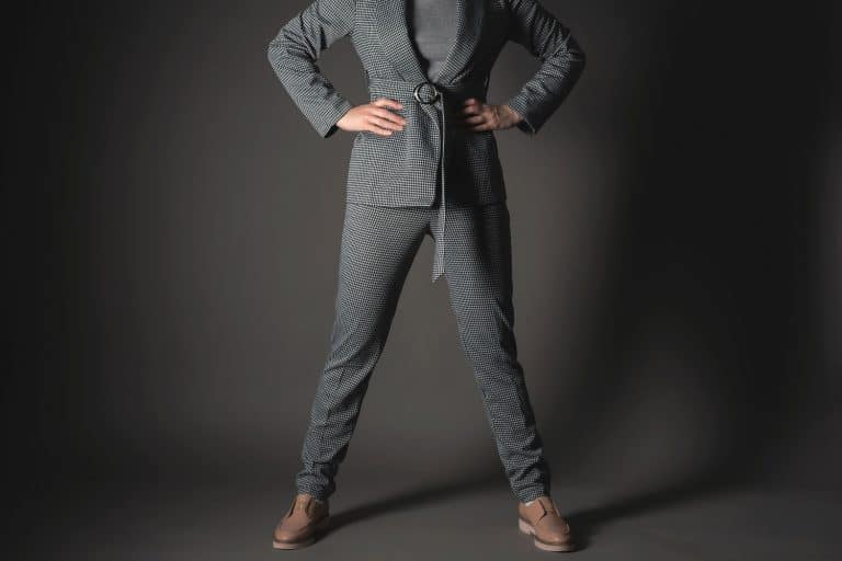 A tall business woman wearing a gray suit and black leather shoes on a dark gray background, What Color Shoes Go With A Gray Suit?