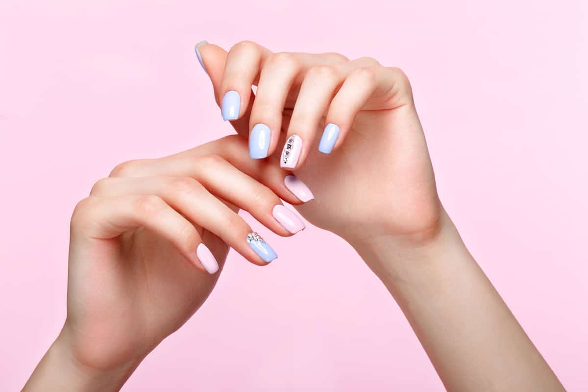 A woman showing her stylish nail art design on a pink background