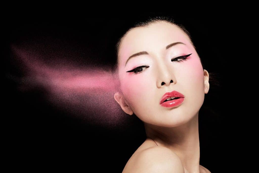 Model with pink powder isolated on black background