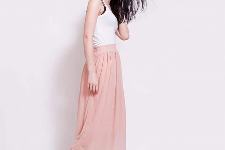 Attractive young brunette woman with perfect natural neutral make-up, freckles and simple hairstyle wearing high heels shoes, pink maxi skirt,white top and gray hat, Can You Wear A Maxi Skirt As A Dress? [Here's How]