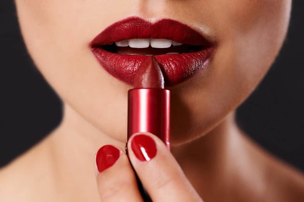 Close up image of a woman applying lipstick
