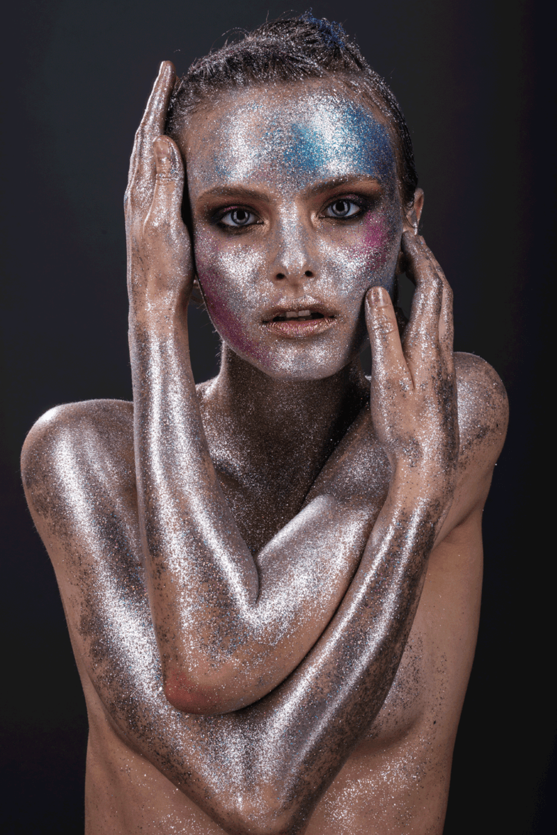 Fashion model with bright makeup and colorful glitter and sparkles on her face and body