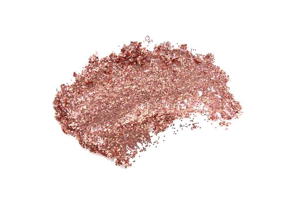 Glitter eye shadow or body smear isolated on white. Beauty, fashion, festive and make up concept.