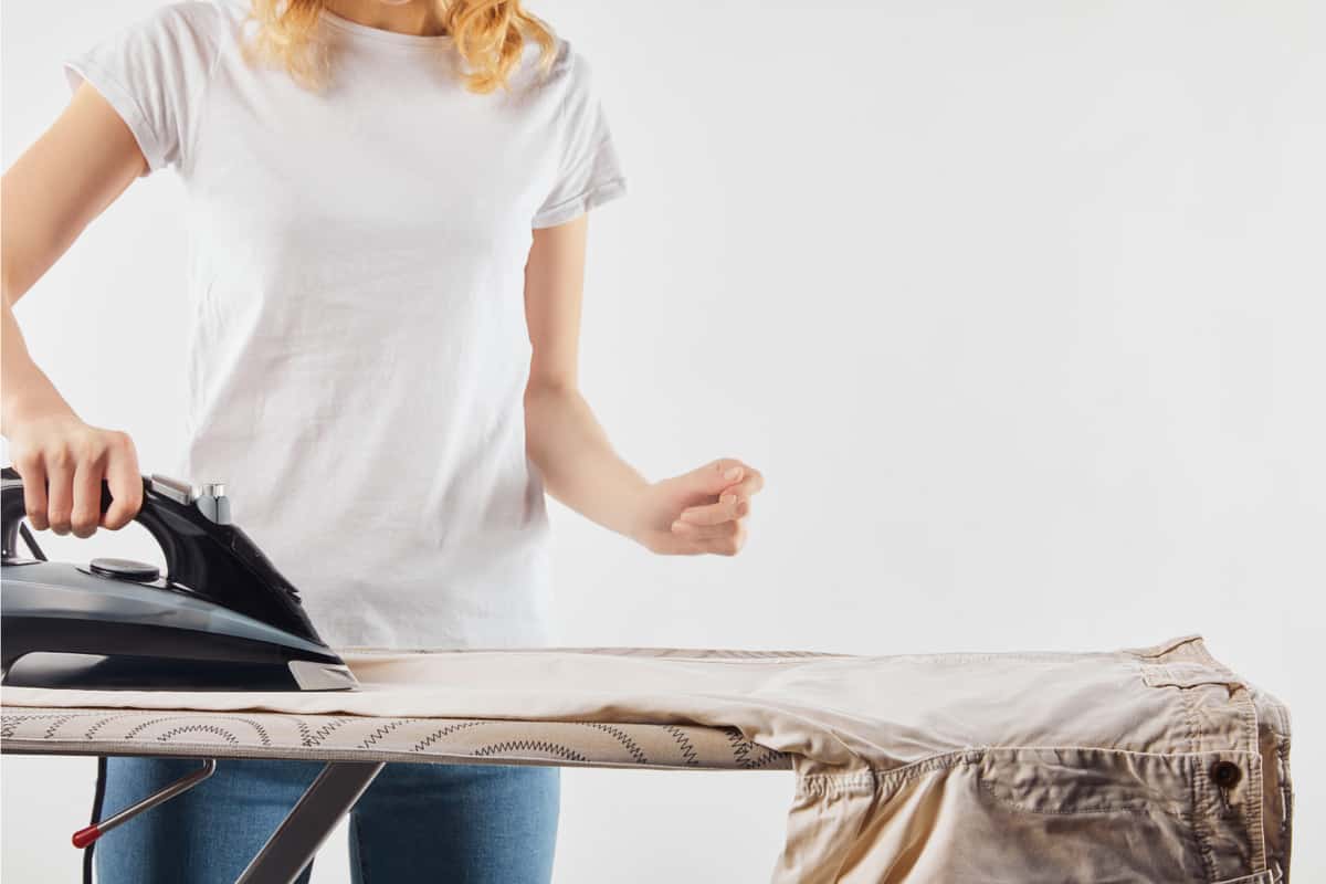 Partial view of woman ironing brown pants isolated on grey