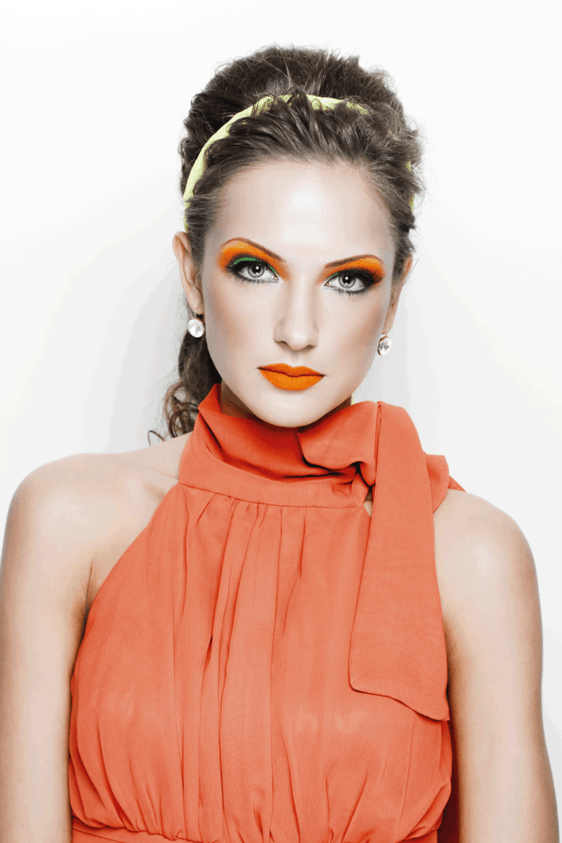 Retrato de uma mulher bonita no vestido laranja e maquiagem